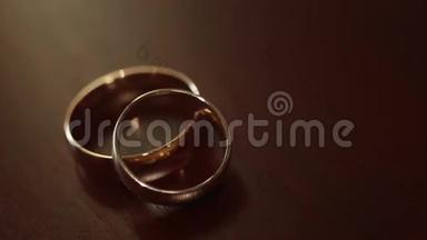米色背景上的金色订婚戒指。 结婚戒指。 婚礼当天有两个华丽的结婚戒指。 两个结婚戒指
